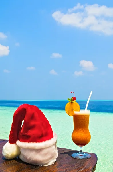 Blisko napoju jest na plaży tabela z Santa hat — Zdjęcie stockowe