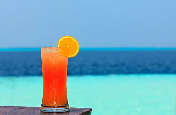 Un vaso de bebida está en una mesa de playa —  Fotos de Stock