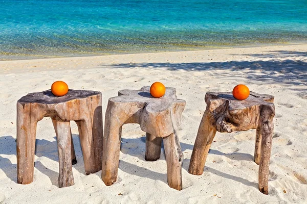 Drei Orangen stehen auf originellen Strandtischen Stockbild