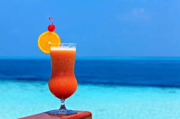 Copo de bebida está em uma mesa de praia — Fotografia de Stock