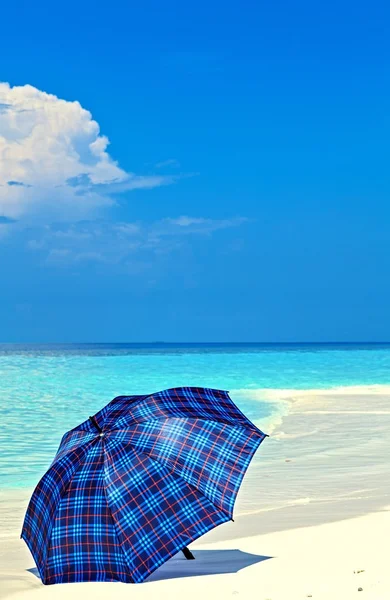 Blå paraply är på en strand — Stockfoto