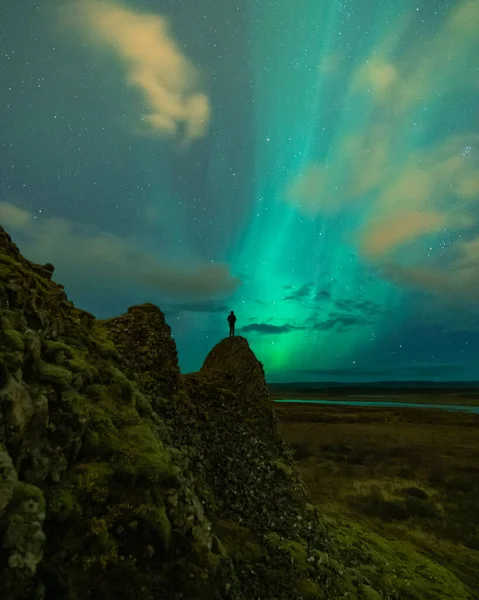 An adventure solo traveler posing with the beautiful northern lights also known as aurora borealis in the background. A breathtaking nature of Iceland as nordic country — Stock Photo, Image