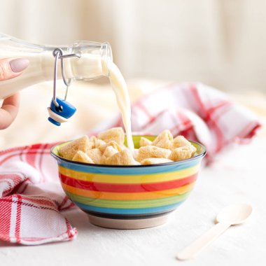 Arka planda bir şişe taze sütle kilden bir kasede gevrek mısır gevreği. Sağlıklı kahvaltı gevrekleri. Amaranth pedleri Boşluğu kopyala, 1: 1