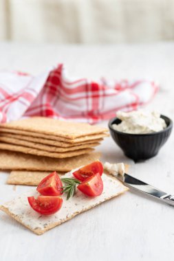 Yumuşak peynirli sağlıklı çıtır çavdar ekmeği, soğanlı ve kiraz domatesli hafif arka planda seçici bir odak noktası. Sağlıklı kahvaltı. Boşluğu kopyala