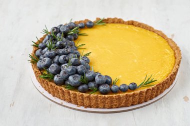 Limonlu tart ve hafif ahşap arka planda taze yaban mersini. Boşluğu kopyala, seçici odak