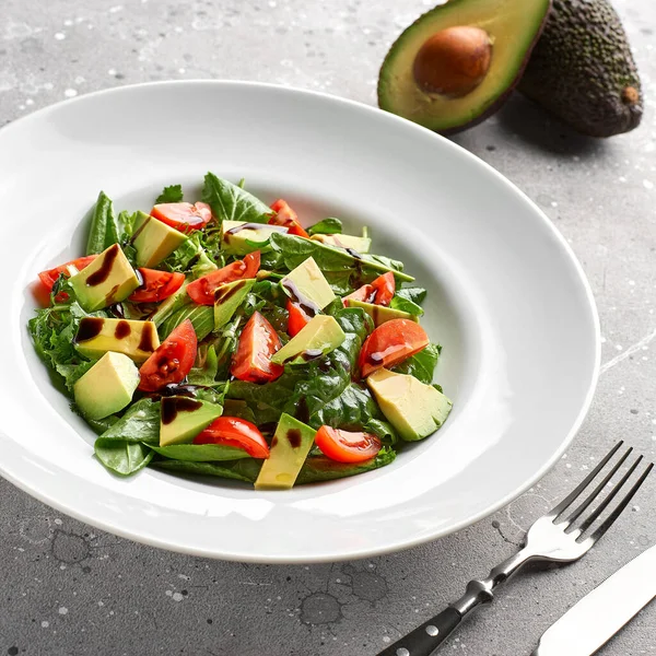 Salade met avocado, sla, tomaat en lijnzaad op grijze ondergrond.Close up — Stockfoto