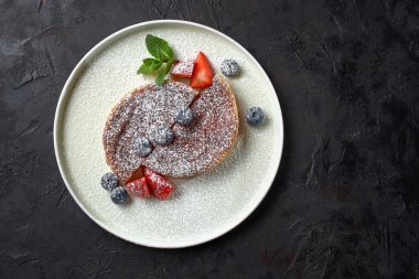 Crack Pie, American dessert with a rich salty-sweet taste on an oatmeal basis, on a black stone background. Banner, Top view.