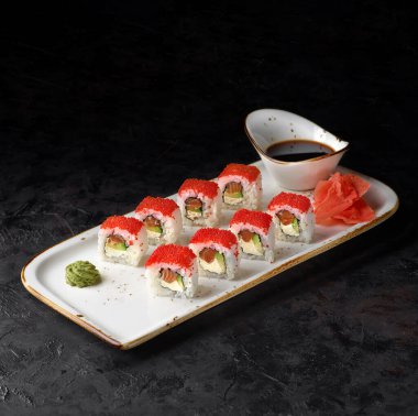 California Maki Sushi peynirli, avokadolu, taze somonlu ve siyah arka planda Tobiko havyarlı. Suşi menüsü. Japon yemeği..
