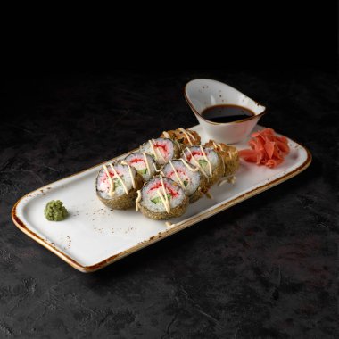 Yengeçli Tempura dürümü. Yengeç, Tobiko havyarı, sos ve siyah desenli arka planda salatalık sarması. Suşi menüsü. Japon yemeği..