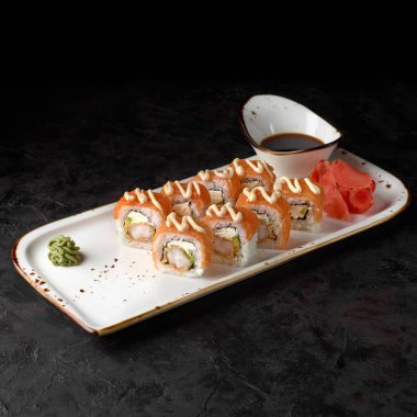 Roll Sushi Bonito peynirli, salatalıklı, tuzlu somon balıklı ve ton balıklı. Geleneksel Japon suşisi siyah arka planda yuvarlanıyor. Suşi menüsü. Japon yemeği..