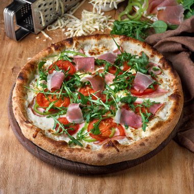 Prosciutto parma jambonlu pizza, ahşap arka planda roka salatası. Piknik şirketi için fast food, menü için fotoğraf. İtalyan mutfağı.
