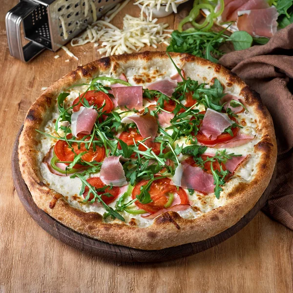 Prosciutto parma jambonlu pizza, ahşap arka planda roka salatası. Piknik şirketi için fast food, menü için fotoğraf. İtalyan mutfağı.