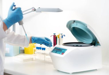 Kadın araştırmacı, laboratuardaki ilaç veya kimyasalların araştırılmasında tüpten hücre nakli için pipette kullanıyor.