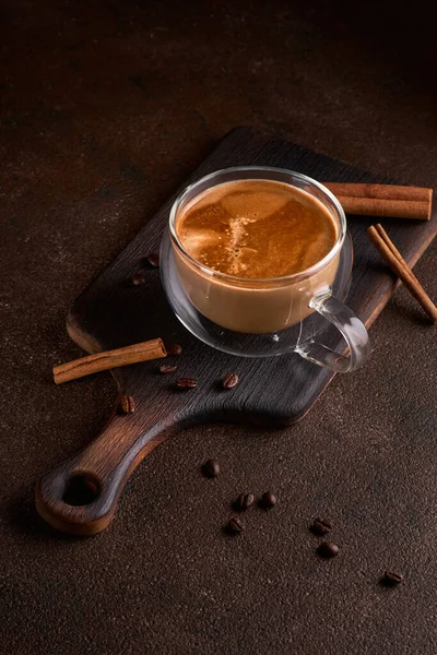 Hot and aromatic coffee spilling from glass cup on the dark background. Concept of tasty refreshment beverage with coffee. Copy space for text, menu or recipe