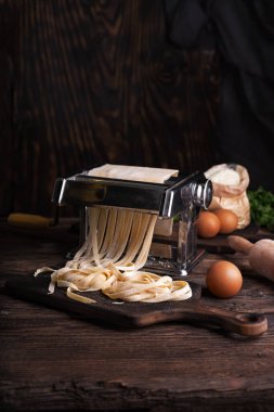 Makarna makinesinde ev yapımı fettucine hazırlıyorum. Geleneksel İtalyan yemeği yapmak için özel ekipman, kopyalama alanı