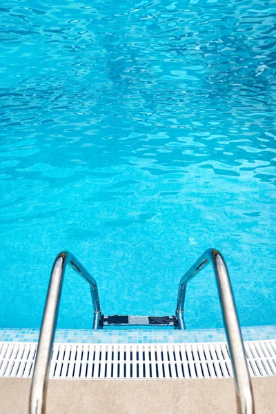 スイミングプールのはしごと青いプールの水の背景のトップステップとクロムハンドレール — ストック写真