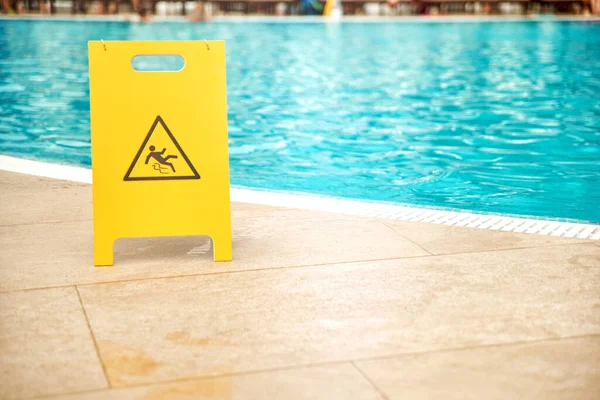 Warning plates wet floor beside the pool Made of yellow plastic. Royalty Free Stock Images