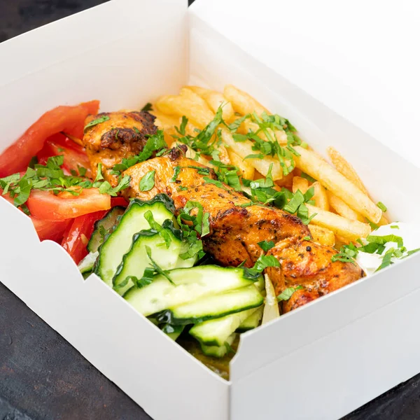 Suministro de comida rápida.El souvlaki griego, la ensalada y los gyros quitan el menú del restaurante de comida rápida servido en platos de papel reciclable en la mesa.. — Foto de Stock