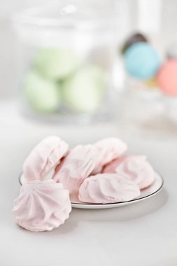 Beyaz tabakta çok renkli lokumlar var. Şekerlemelerle dolu bir hayat Işık masasında pembe.