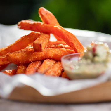 Ahşap tabakta guacamole soslu fırında patates dilimleri, gri arka plan. Vejetaryen gıda konsepti.