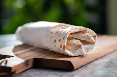 Shawarma, sandviç, jiroskop, bir rulo taze lavaş, döner kebap. Tam, kesilmemiş. Tahta tabakta servis ediliyor. Geleneksel doğu yemekleri, sokak yemekleri menüsü.