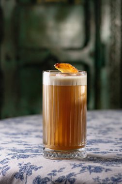 Tatlı Balkabağı kokteyli, bardakta alkollü içecek, arka planda duvar. Kokteyl masanın üstünde..