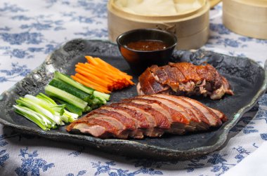 Traditional Peking duck served with cucumber slices, scallions, and hoisin sauce, styled for an elegant feast.