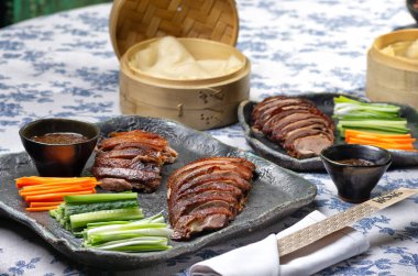 Traditional Peking duck served with cucumber slices, scallions, and hoisin sauce, styled for an elegant feast.