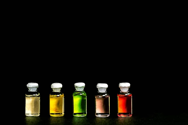 Siyah arka planda şişe içinde aroma yağı koleksiyonu. Küçük cam şişelerdeki temel yağlar..
