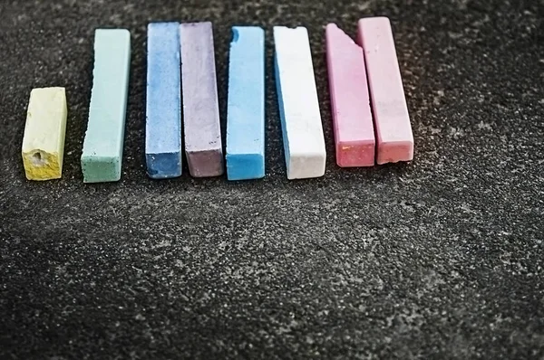 Çocuklar asfalt yolda tebeşirle boyanmış. Sokaktaki çocuk parkında çok renkli tebeşirler. Kopyalama alanı olan tebeşirli çocukların seçmeli odak arkaplanı. 