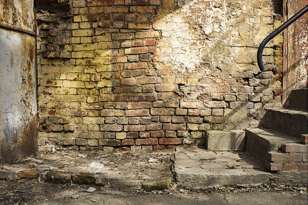 Sarı ve kırmızı tuğlalı duvarları, paslı metal kapıları ve beton merdivenleri olan eski sanayi arka bahçesi. Eski tuğla duvarlı Grunge arkaplanı.