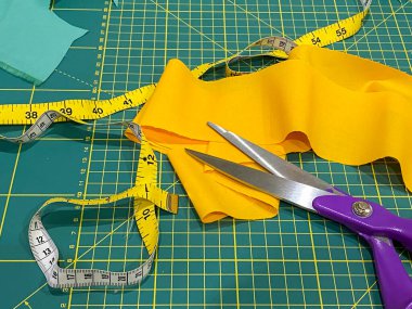 Boyama makası, mezura ve ölçü işaretli sarı kumaş.