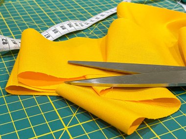 Boyama makası, mezura ve ölçü işaretli sarı kumaş.