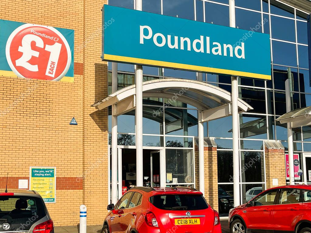 Llantrisant, Wales - December 2020: Front exterior view of the entrance to a branch of the Poundland chain of discount shops, with cars parked in front.