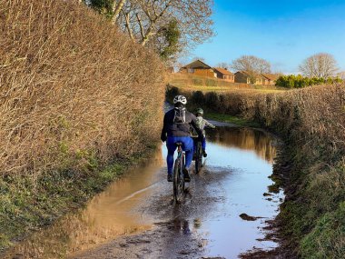 Pontypridd, Galler - Aralık 2020: İki kişi fırtınadan sonra dar bir şeritte bir sel baskını düzenliyor.