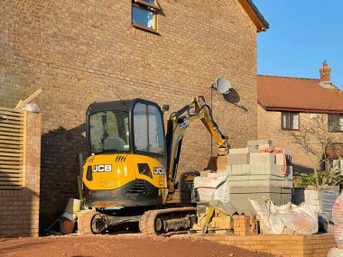 Pontypridd, Wales - January 2021:  Mini excavator parked outside a house which is undergoing renovation and extension clipart
