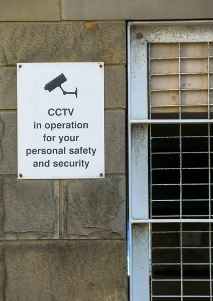 Sign on the wall of a car park building explaining CCTV is in operation. No people.