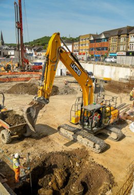 Pontypridd, Galler - Mayıs 2018: Mekanik kazıcı, eski Taff Vale Precinct 'in sahasında büyük bir yeni karma kullanım geliştirme projesi olan yenilenme projesinin temellerini hazırlıyor.