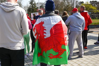Cardiff, Wales - Nisan 2021: Cardiff şehir merkezinde bir grup insanın içinde Galler bayrağına sarılmış kişi