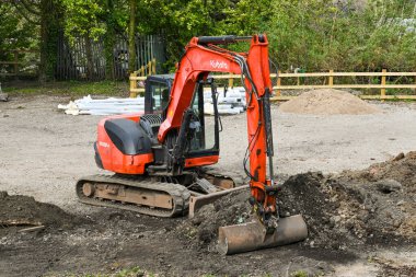 Pontypridd, Wales - April 2021: Small mechanical digger being used to clear waste ground in Pontypridd. clipart
