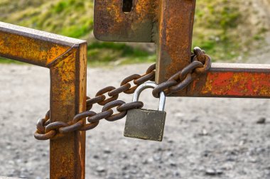 Kapıların etrafına asma kilit takılmış ağır metal bir zincir yakın görüntü. Kimse yok..