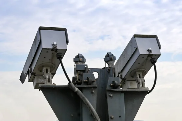 Pair of remote controlled CCTV video cameras isolated against a clear sky. No people.