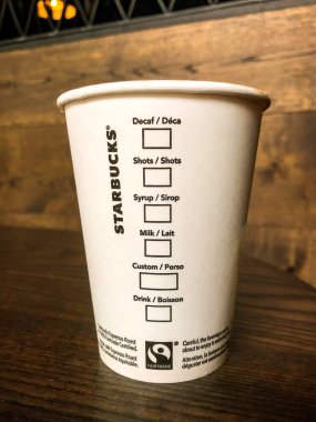 Cardiff, Wales - Mart 2018: Starbucks 'ın içindeki bir masada tek kullanımlık kağıt bardak. Bardağın yanında sıcak içecek için seçenekler listesi var.