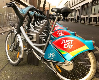 Dublin, İrlanda - Şubat 2018: Bisiklet paylaşım şeması şehir merkezindeki bir sokakta raflarda park edilmiş bisiklet. Bisikletlerin sponsoru Just Eat