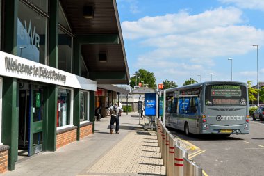 Didcot, İngiltere - Haziran 2021: Didcot Parkway tren istasyonunun girişi ve otobüs durağının önünde park edilmiş bir otobüs. Demiryolu ve otobüs yolculuğu arasında bağlantıları olan bir ulaşım merkezi..