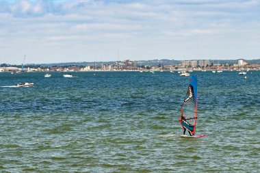 Poole, İngiltere - Haziran 2021: Poole Limanı 'nda dalgalı su üzerinde rüzgar sörfçüsü.