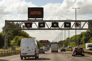 Bristol, England - June 2021: Overhead gantry on the M4 motorway with road signs showing the speed limit and a closed lane. clipart
