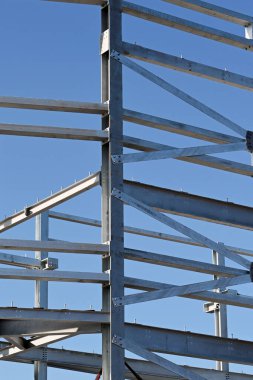 Mavi gökyüzüne karşı çok katlı yeni bir ticari binanın çelik yapı iskeletinin yakın görüntüsü. Kimse yok..