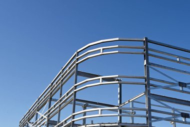 Mavi gökyüzüne karşı çok katlı yeni bir ticari binanın çelik iskeleti. Kimse yok.. 