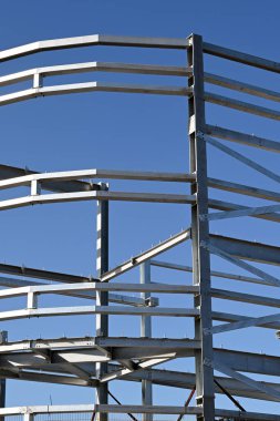 Mavi gökyüzüne karşı çok katlı yeni bir ticari binanın çelik iskeleti. Kimse yok..